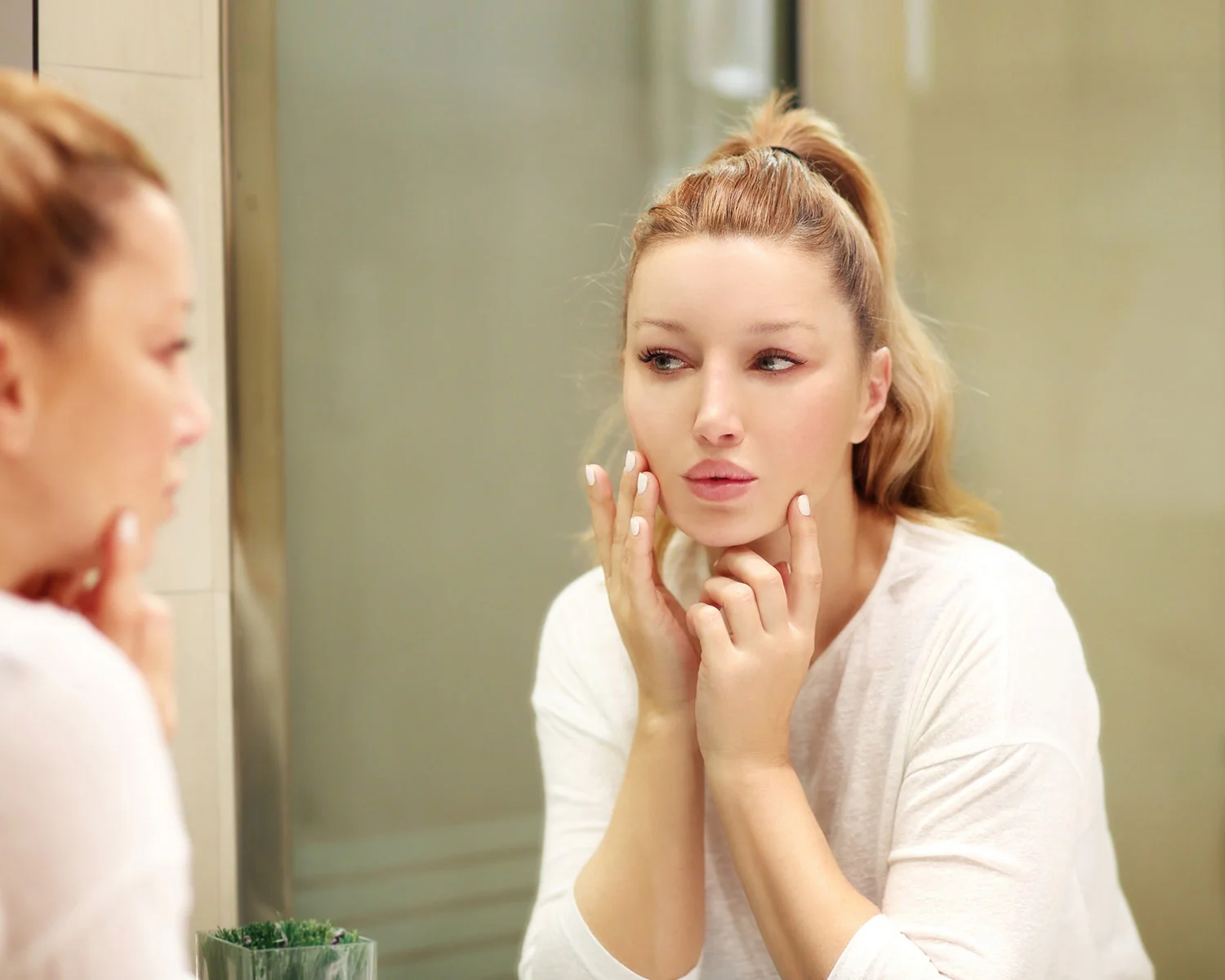 Woman inspecting her facial skin in the mirror