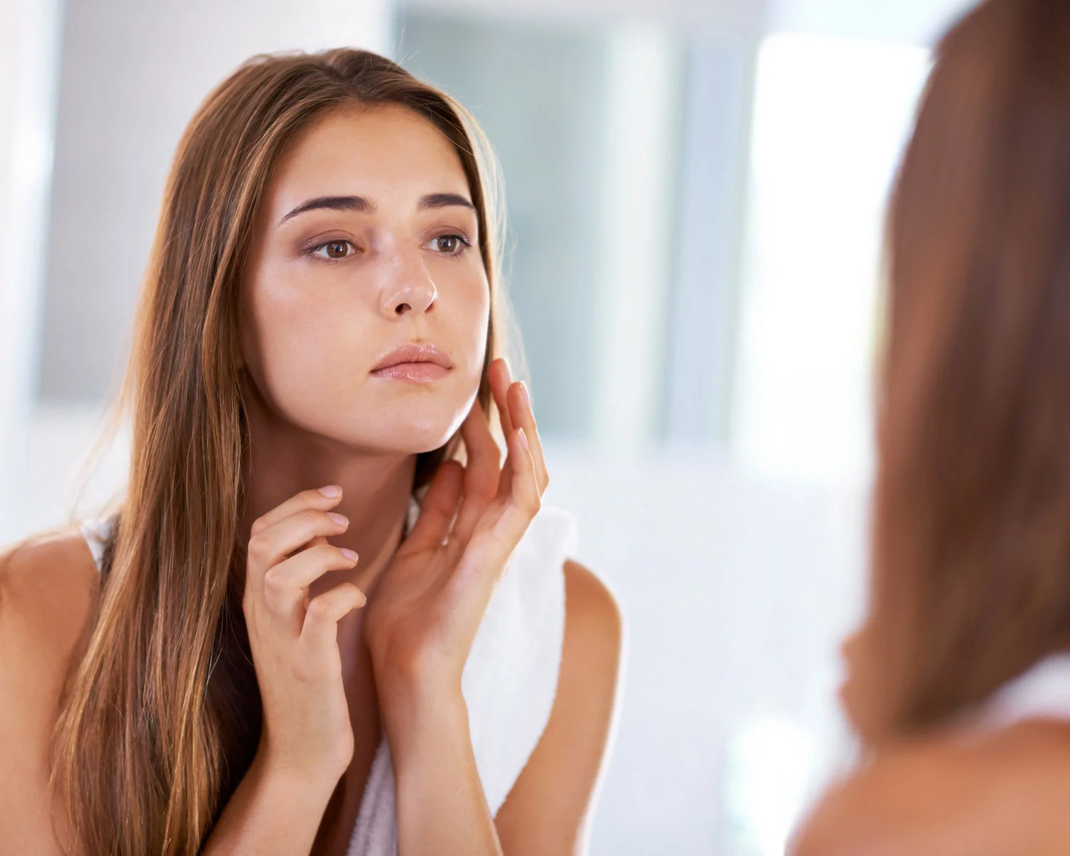 Woman admiring her face in a mirror | BroadBandLight Therapy Lansing