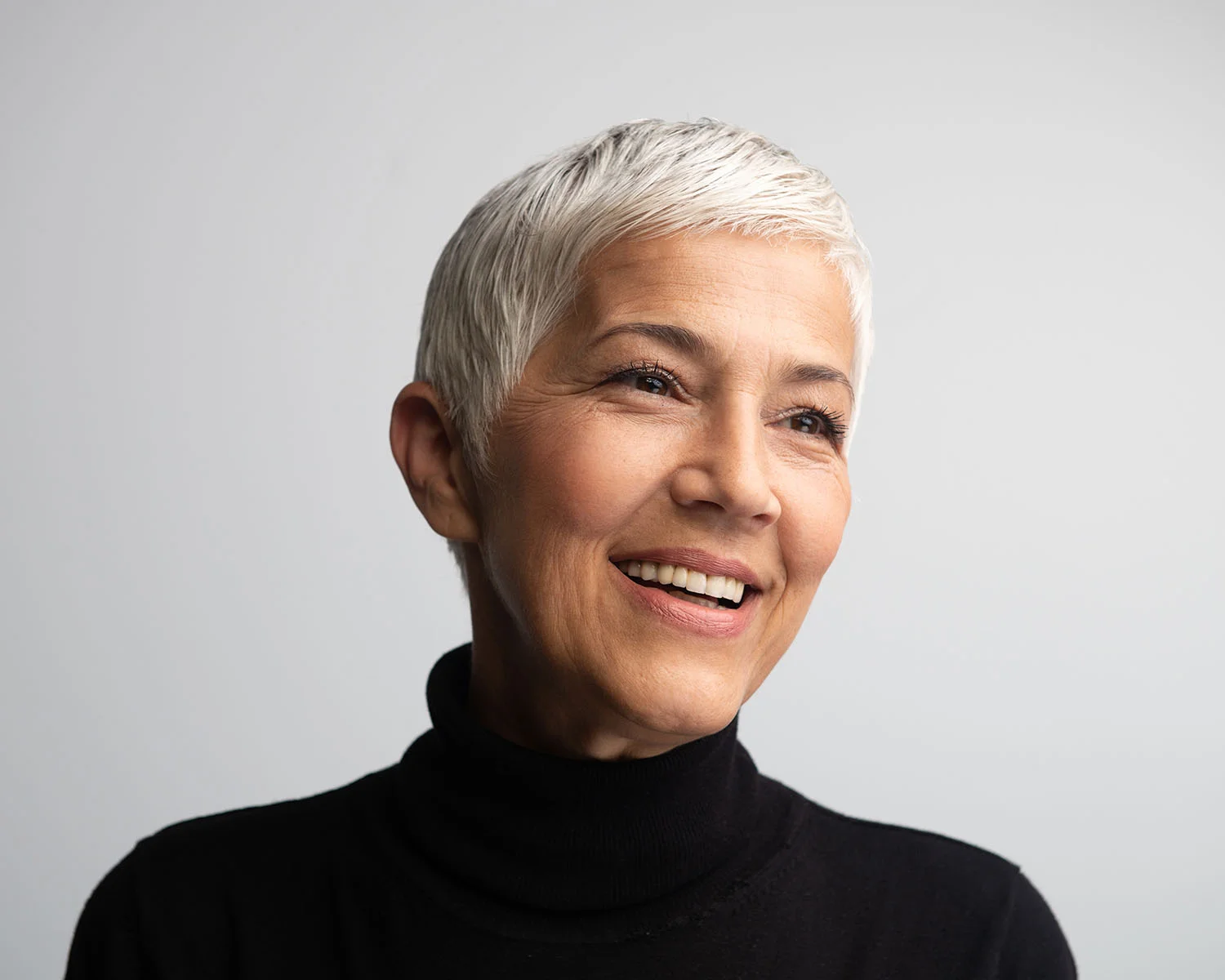 Older woman in a black turtle neck with smooth, younger looking skin